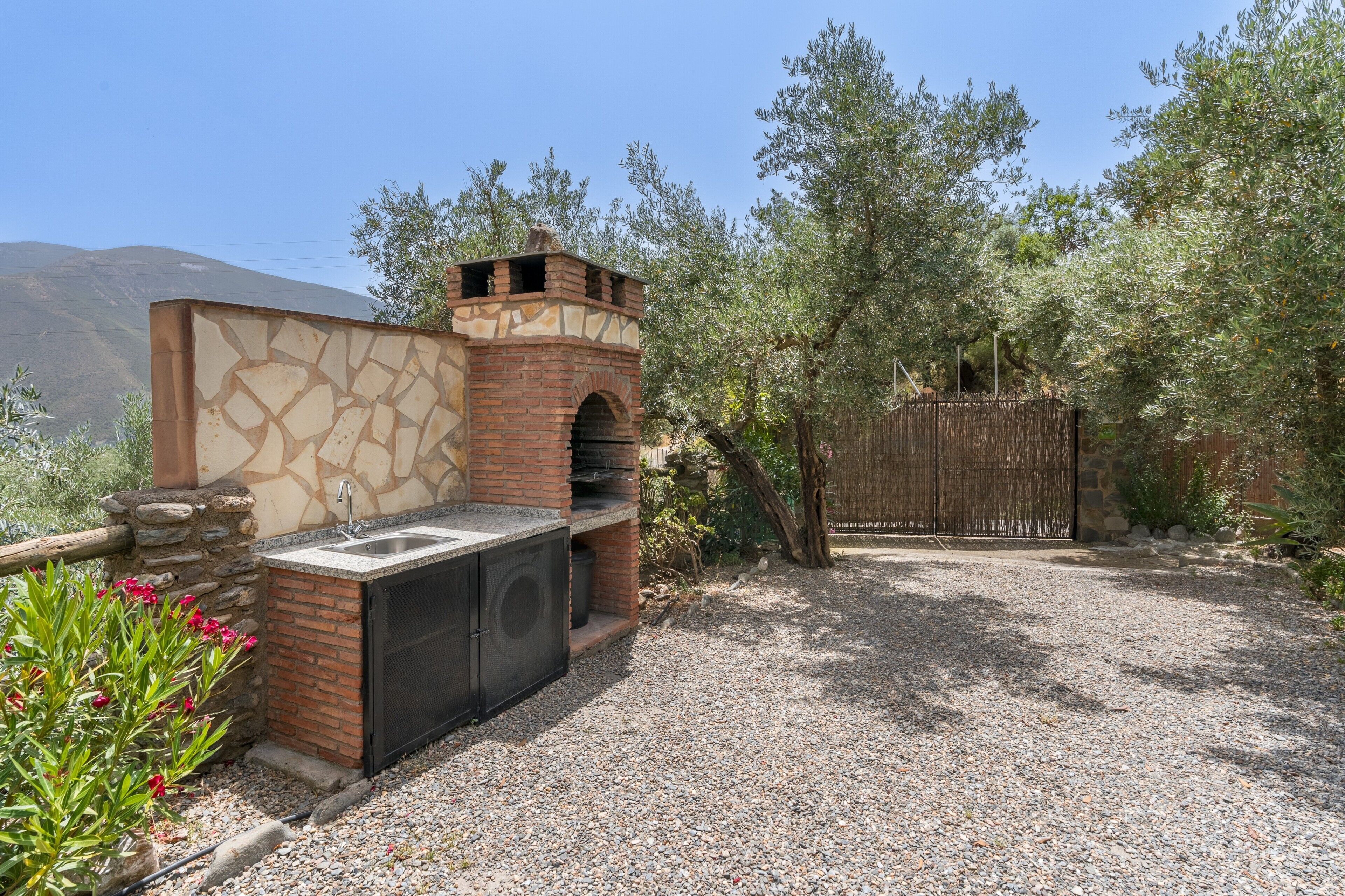 An outdoor kitchen with a stone wall, a brick oven, and a sink.