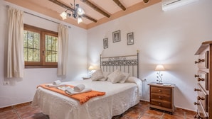 A bedroom with a bed, nightstands, a dresser, and a window with curtains.