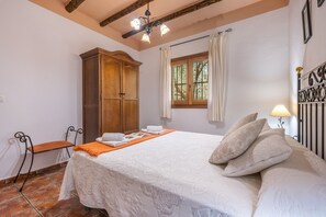 Ein Schlafzimmer mit einem Bett, einem Holzschrank, einem Fenster mit Vorhängen, einem Nachttisch und einer Lampe.