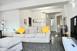A modern living room with a sofa, a television, and a floor lamp.