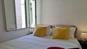 A hotel room with a bed, pillows, a window, and a bedside lamp. - Apartment 'Monti View' with Private Terrace, Wi-Fi and Air Conditioning (Roma)