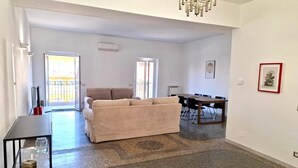 A spacious living area with a sofa, a dining table, and a chandelier. - Apartment 'Monti View' with Private Terrace, Wi-Fi and Air Conditioning (Roma)