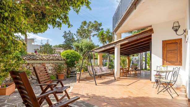 A patio with wooden furniture, a swing, and a covered seating area.