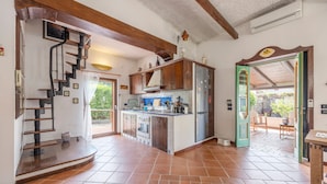 A kitchen with a central island, wooden staircase, and a view to an outdoor patio.