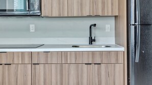 A kitchen with wooden cabinets, a stainless steel refrigerator, a black faucet, and a microwave.