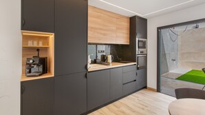 A modern kitchen with dark cabinetry, a wooden countertop, and a coffee machine.