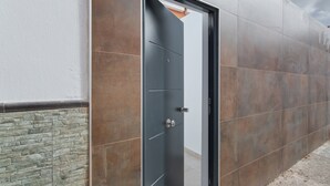 A modern building exterior with a door, stone wall, and metal panels.