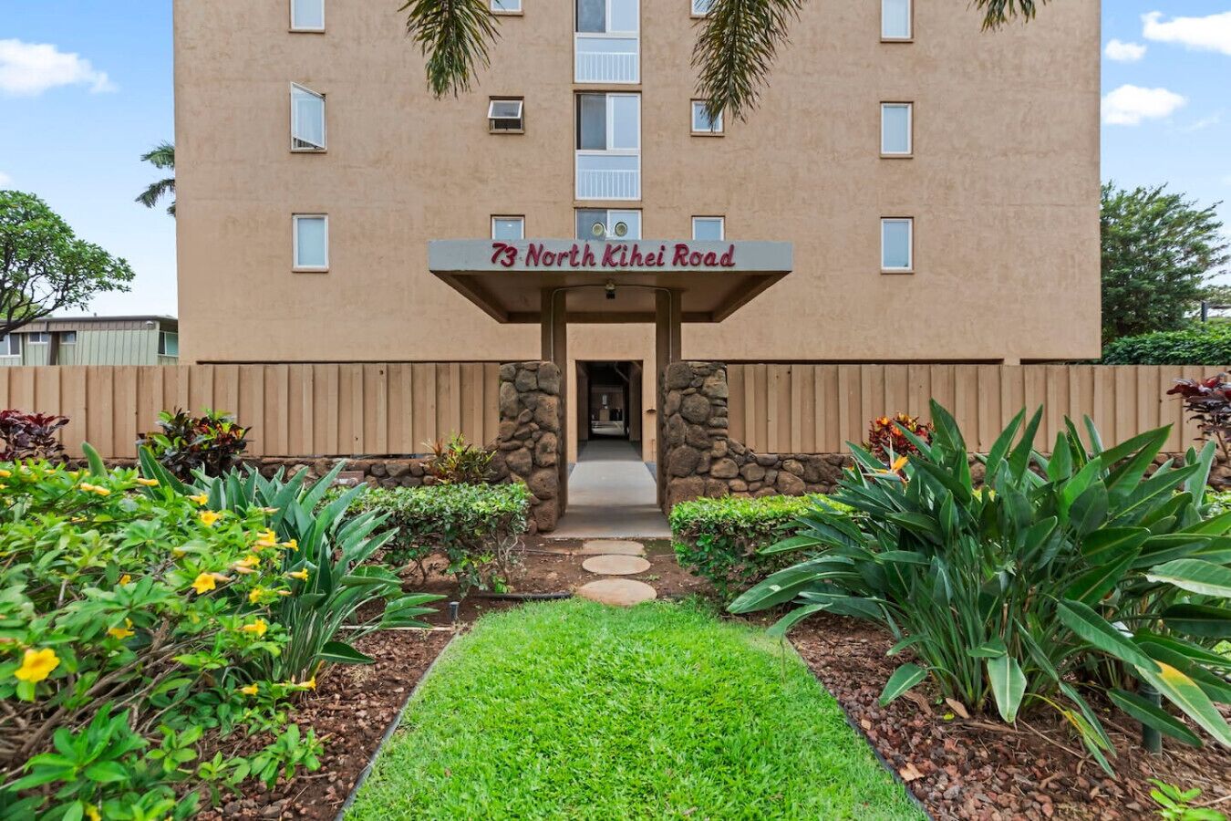 A building with a sign reading '73 North Kihei Road' and a pathway leading to the entrance.