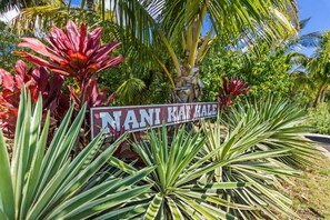 Une pancarte portant l’inscription « NANI KAI KALE » et entourée de plantes tropicales.