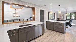A modern kitchen with a large island, dark cabinets, and a white countertop.