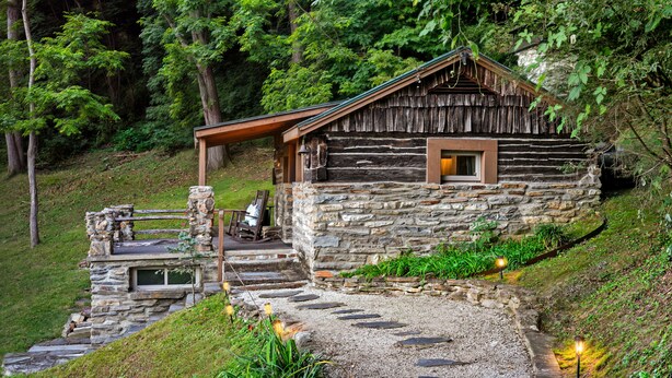A rustic cabin with a stone exterior, a wooden porch, and a small window.