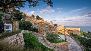 A coastal property with stone buildings, a stone staircase, and a paved pathway.