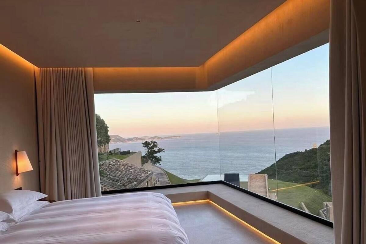 Une chambre avec une grande fenêtre donnant sur un paysage côtier.