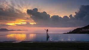 A person standing in a swimming pool with a sunset in the background.
