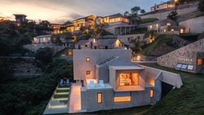 Una villa moderna con un amplio espacio exterior, una piscina y un interior bien iluminado.