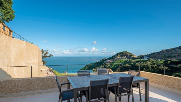 Un patio al aire libre con mesa y sillas que da a vistas costeras.