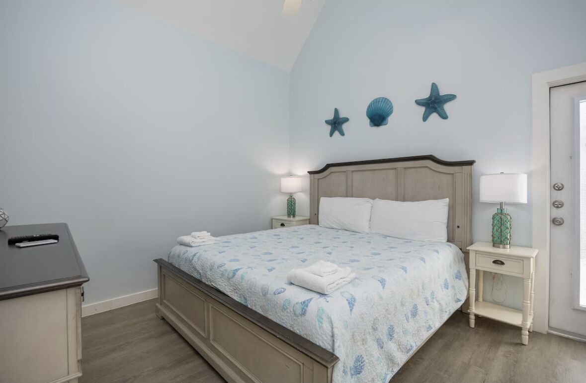 Una camera da letto con un letto, due comodini, una scrivania e una porta.