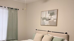 Ein Schlafzimmer mit einem Bett, einem Deckenventilator, einem Gemälde und einem Nachttisch.