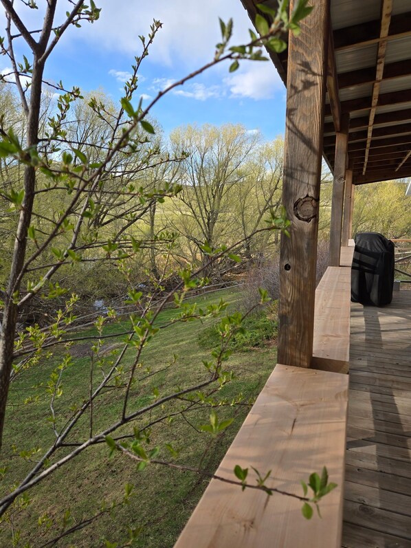 Terraza de madera con vista a un área verde y árboles.