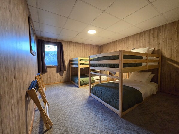 A bunk bed room with wooden walls and a window.