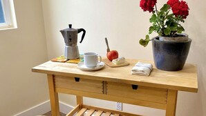 A wooden table with a coffee maker, a cup, a book, a small apple, and a potted plant. - Charming 1-bedroom apartment close to downtown Seattle! (Seattle)