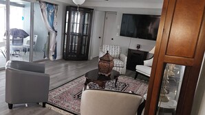Un salon avec un téléviseur, une cheminée et une grande fenêtre.