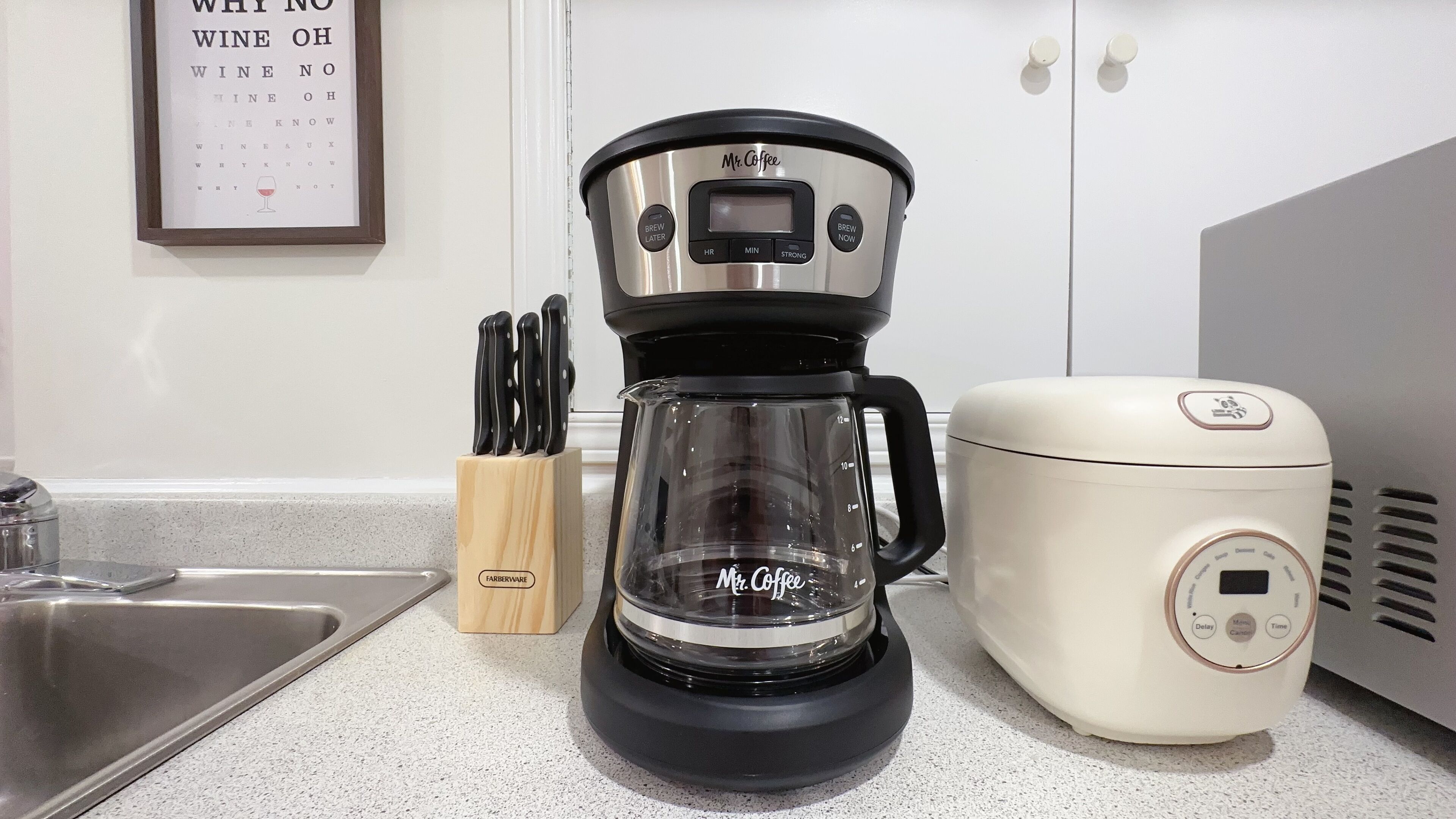 A kitchen with a Mr. Coffee coffee maker, a Farberware knife block, and a white appliance.