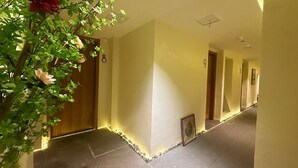 A hallway with a tiled floor, a wooden door, and a plant with flowers.