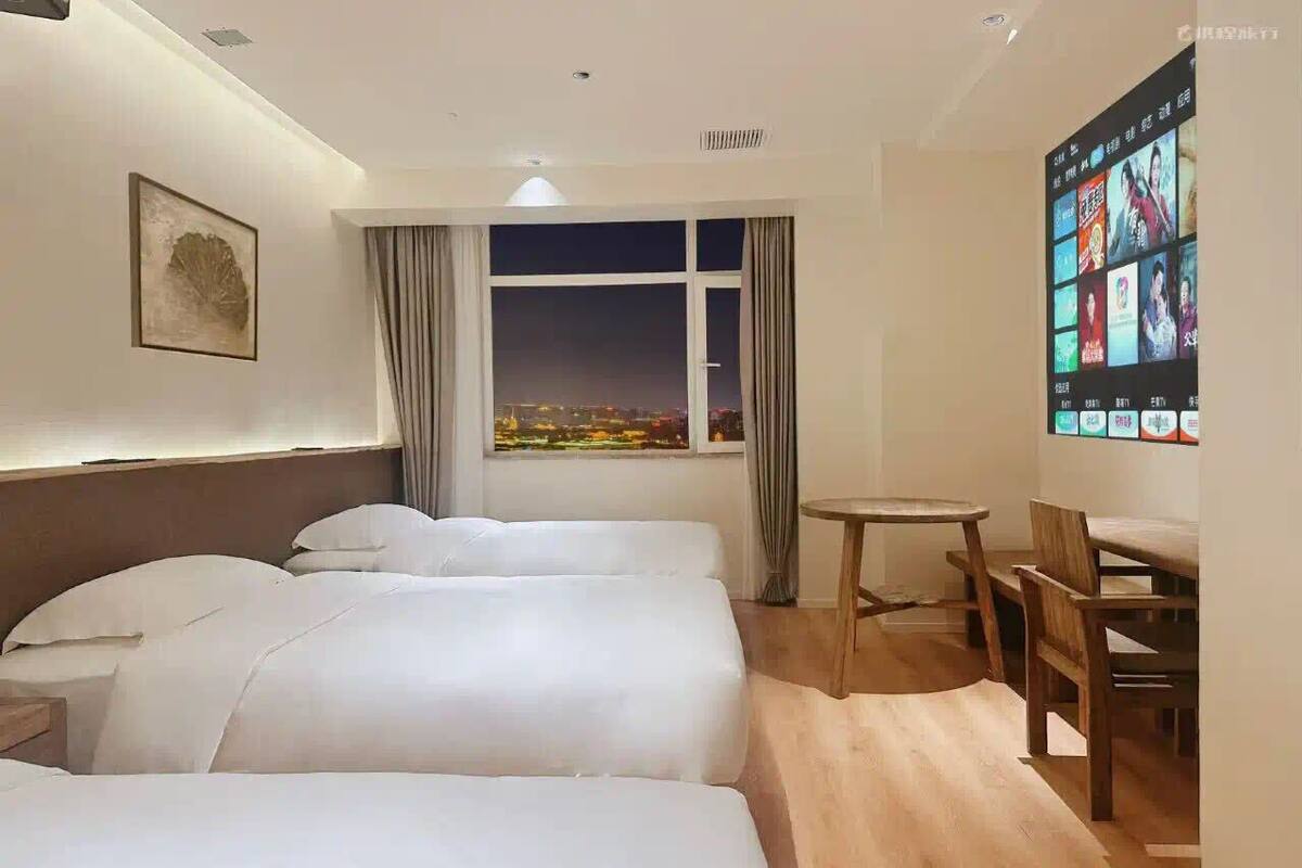 Camera d'albergo con due letti, un piccolo tavolo e una TV che mostra film tra cui scegliere.