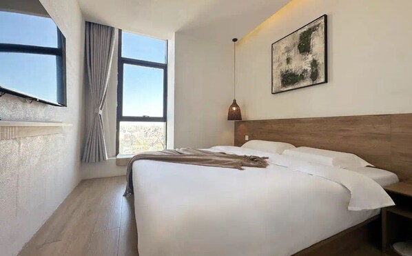 A modern hotel room with a large bed, a wooden headboard, a window with curtains, a wall-mounted artwork, and a pendant light. - Chenshe Hotel Xiaonanmen Morning Market (Xi'an)