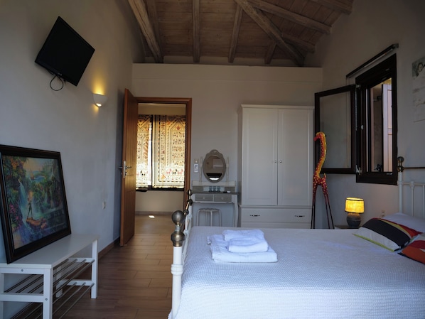 Un dormitorio con cama, televisión, armario y escritorio.