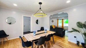 A modern dining area with a wooden table, black chairs, and a pendant light.