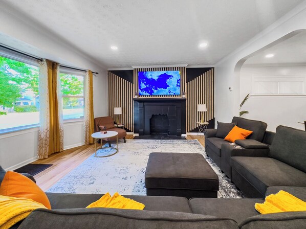 A modern living room with a fireplace, a television, and a sofa with cushions.
