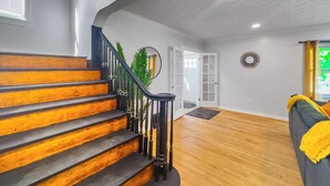 A staircase with wooden steps and black railings, leading to a room with a wooden floor and a large mirror on the wall.