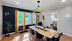 A modern dining room with a wooden table, black chairs, and a pendant light.