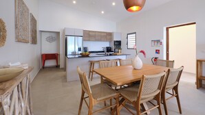 Una cocina moderna con armarios de madera, una isla central y un comedor con mesa de madera y sillas de mimbre.