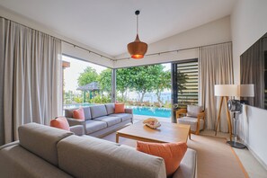 Un salon moderne avec un canapé, une table basse et une vue sur une piscine et un espace verdoyant.