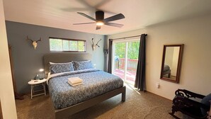 Un dormitorio con cama, ventilador de techo, ventana, puerta y espejo.