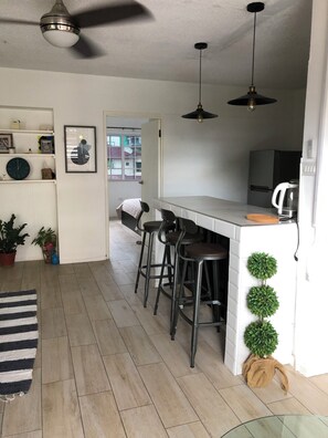 A modern kitchen with a bar area, wooden flooring, and a ceiling fan.