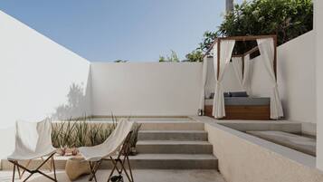 Un patio al aire libre minimalista con una cama de madera, un dosel y una mesa con sillas.