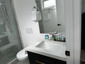 A bathroom with a white sink, a mirror, and a shower area.