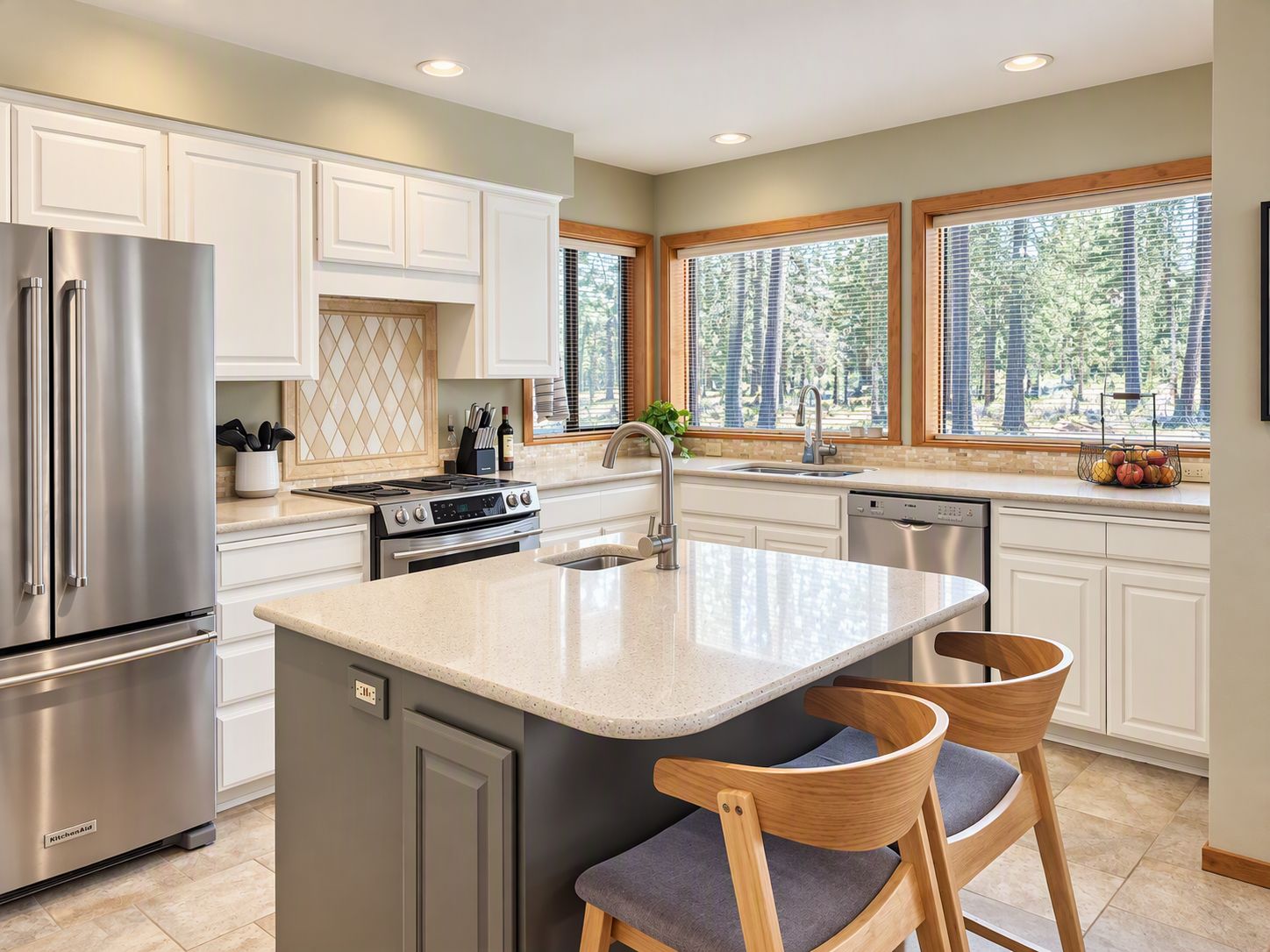 A modern kitchen with a central island, stainless steel appliances, and a view of the outdoors through large windows.
