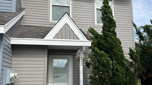 A two-story house with a grey siding exterior, a front door with a small porch, and a mailbox. - Charming 2-bedroom condo with WiFi, AC in gorgeous Kitty Hawk (Kitty Hawk)