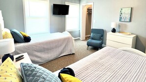 A hotel room with two beds, a ceiling fan, a TV, a chair, and a desk with a lamp. - Charming 2-bedroom condo with WiFi, AC in gorgeous Kitty Hawk (Kitty Hawk)