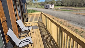 A wooden deck with chairs and a small building in the background. - Shadow Ridge Tiny Home (Big Cabin)