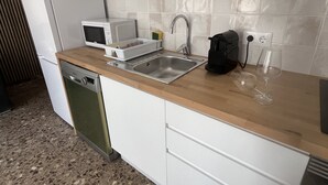 Une cuisine moderne avec des meubles blancs, un évier en acier inoxydable, un four à micro-ondes et un lave-vaisselle.