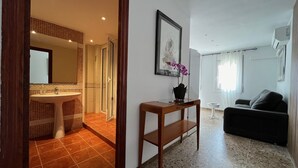 Un salon moderne avec un canapé, une petite table sur laquelle est posé un vase, et un tableau encadré accroché au mur.