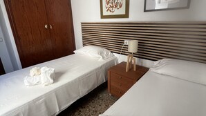 Une chambre d’hôtel avec deux lits simples, une armoire en bois et une table de chevet avec une lampe.