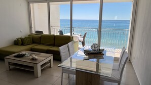 Un salon moderne avec une table en verre, un canapé et un balcon offrant une vue sur la mer.