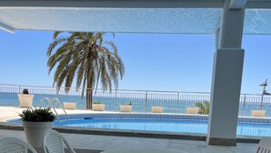 Un espace extérieur abrité avec des sièges, une piscine et une vue sur la mer.